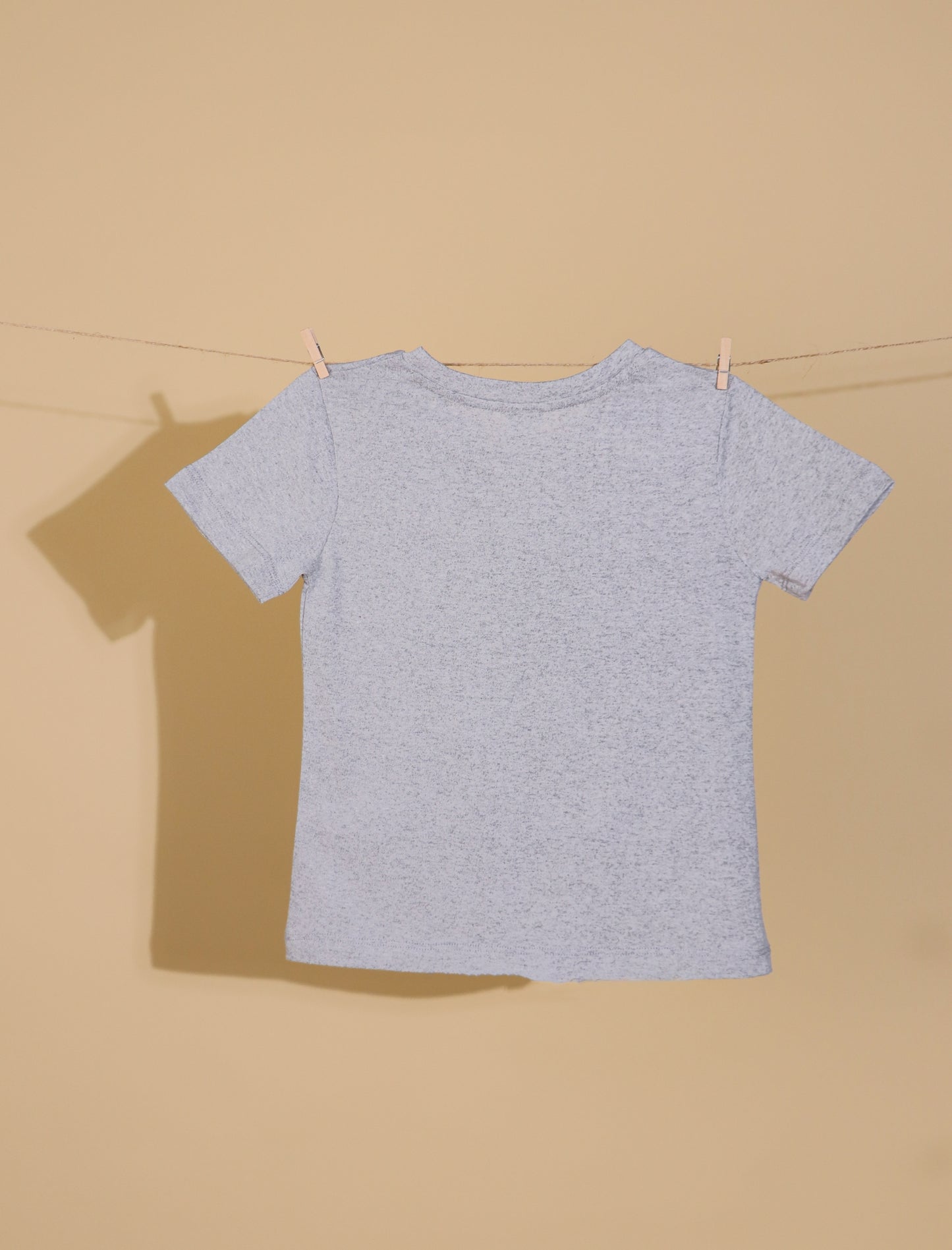 Gray t-shirt on a clothesline against a beige background