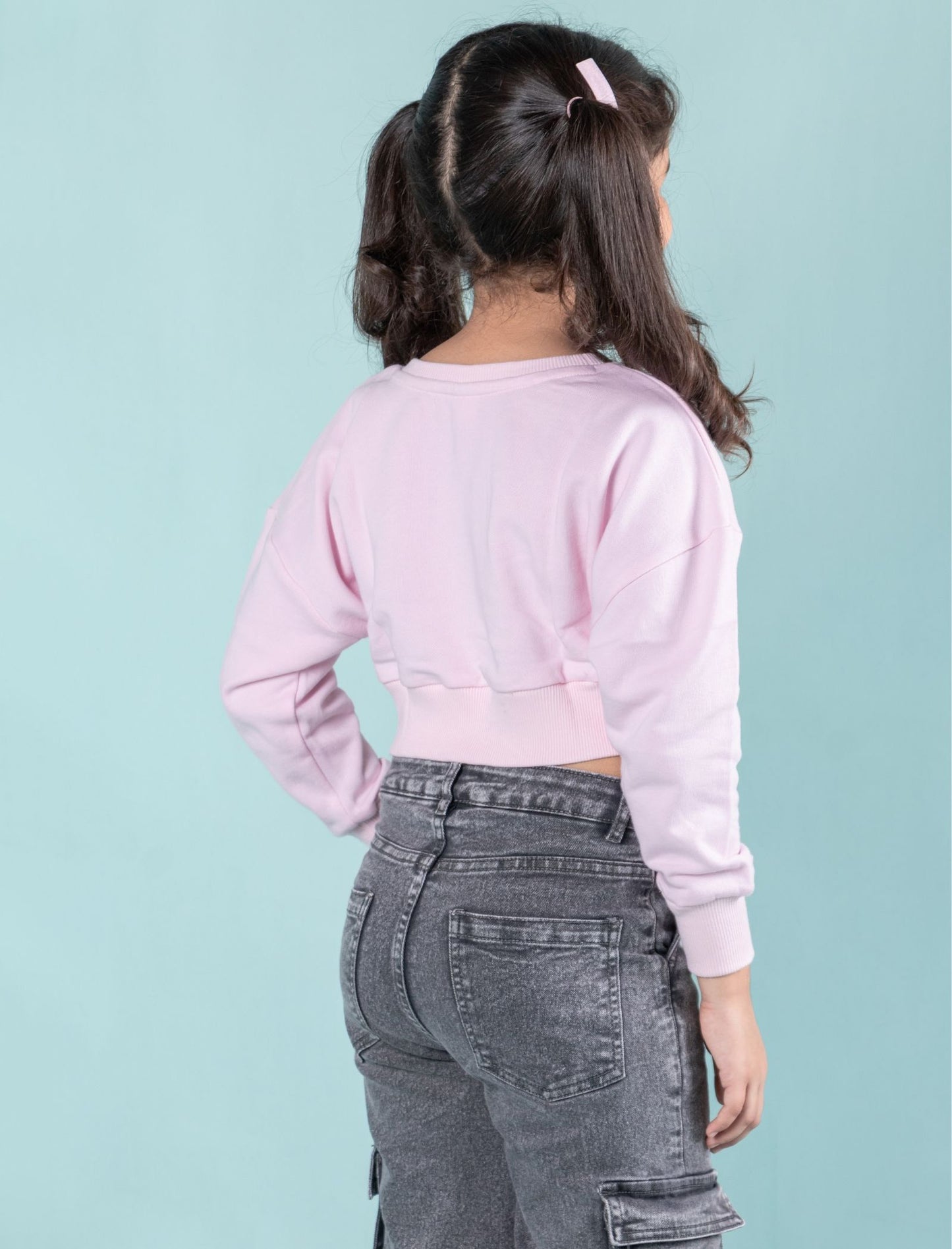 Girls wearing a winter sweatshirt pink colour and gray pants against a light blue background