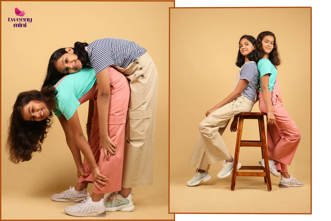 Two girls wearing cotton dungarees and t-shirts posing playfully in a studio setting