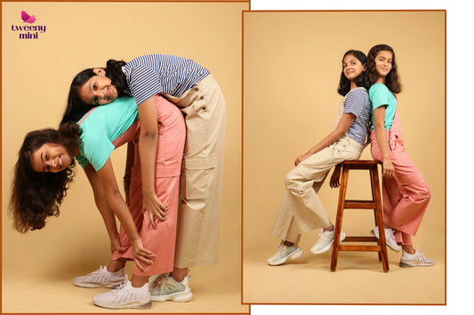 Two girls wearing cotton dungarees and t-shirts posing playfully in a studio setting