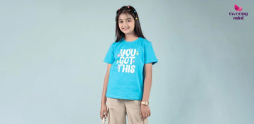 Smiling girl wearing blue graphic t-shirt and beige pants, kids fashion photoshoot
