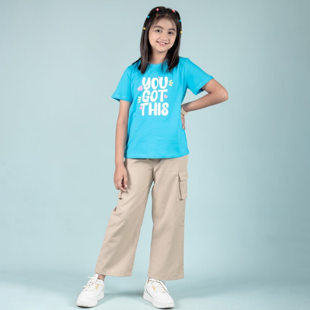Smiling girl in blue graphic t-shirt and beige cargo pants, kids fashion outfit