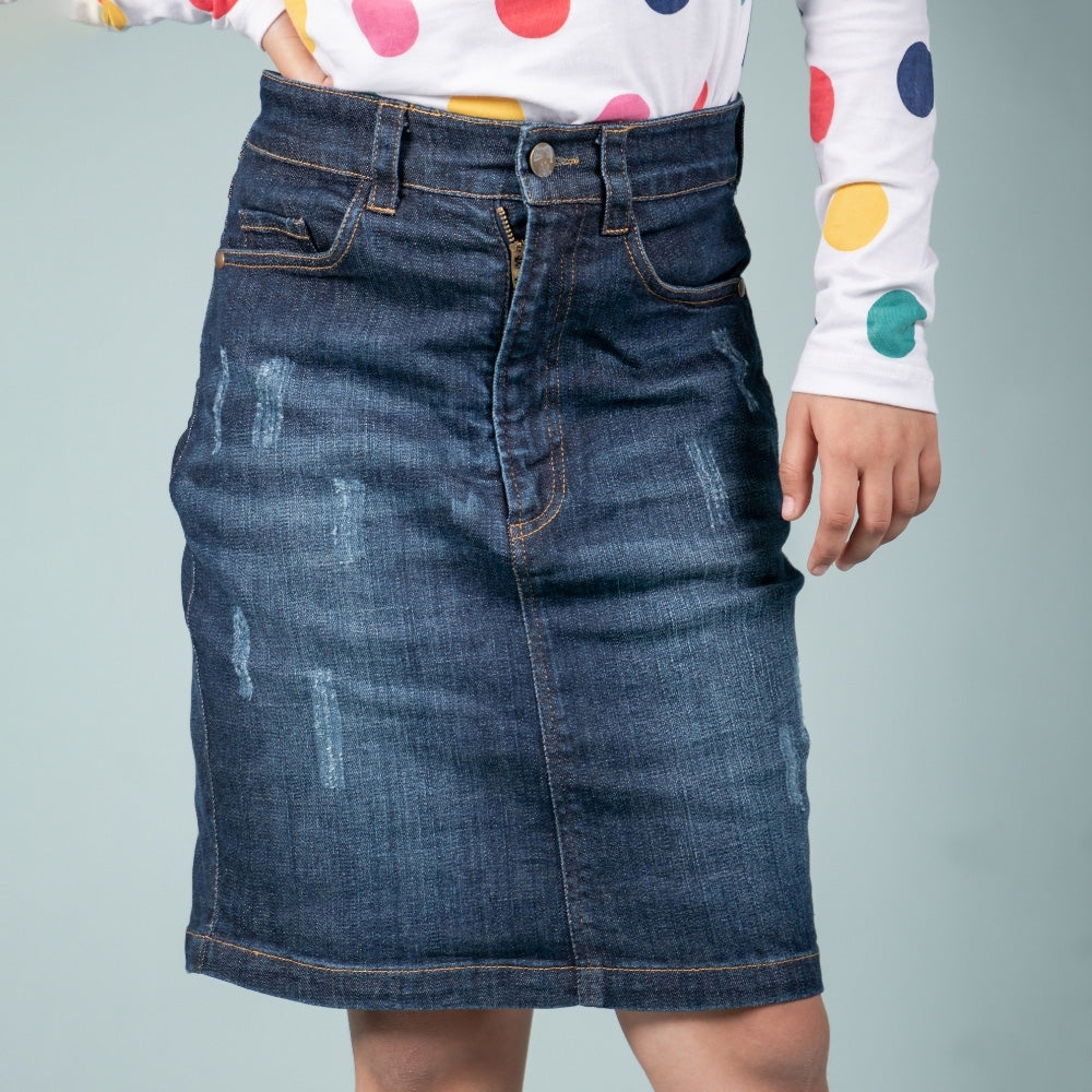 Girl wearing a blue denim skirt with slight distressing, paired with a colorful polka dot top