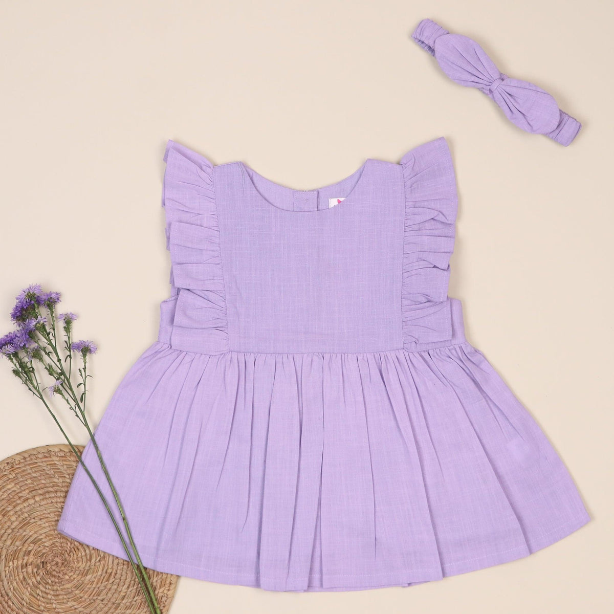 Lavender infant dress with ruffle sleeves and matching headband, styled with purple flowers