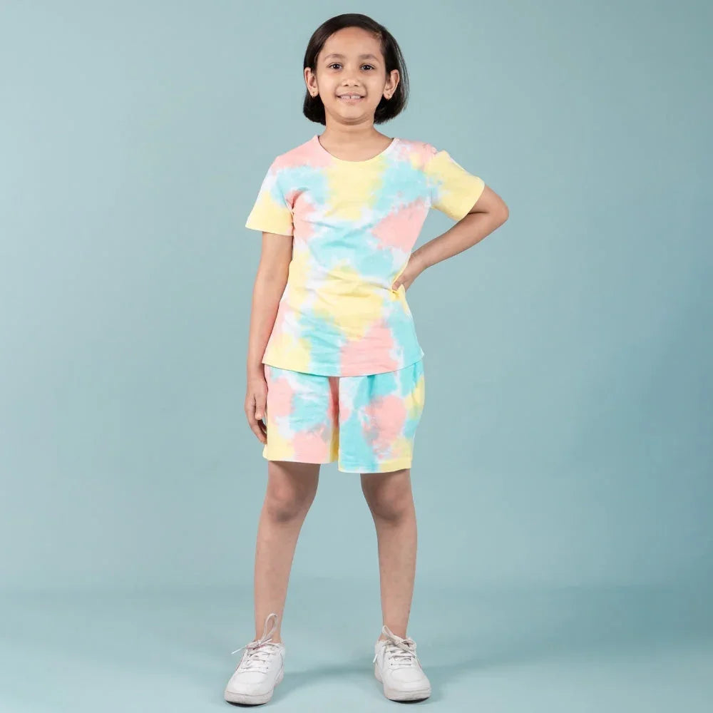 Girl in pastel tie-dye nightdress set with shorts, posing against a light blue background