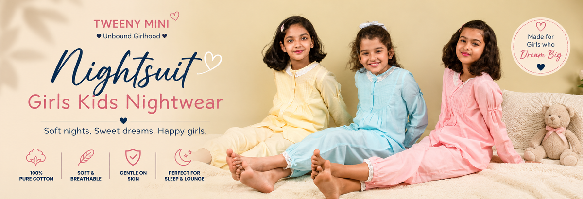 Three girls in colorful floral night suits sitting and smiling on a bed in a cozy room.