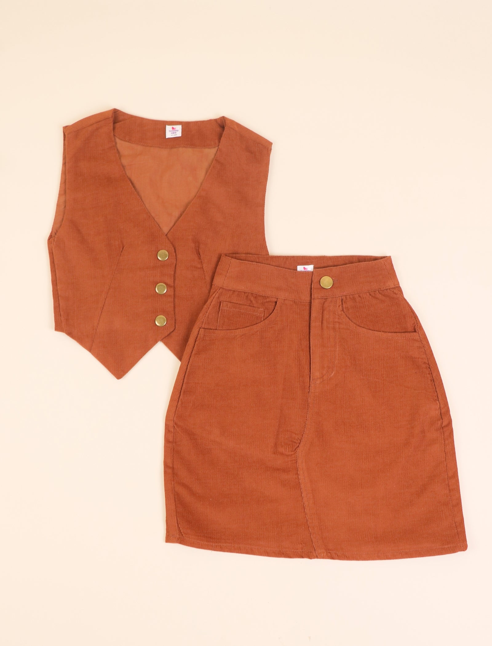 Rust corduroy vest and skirt set on a beige background
