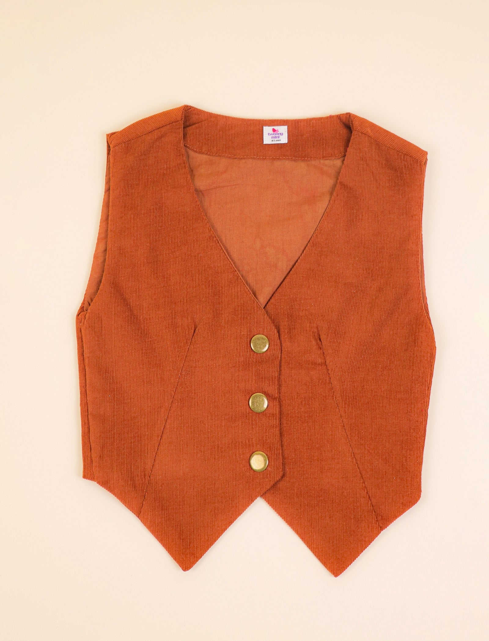 Rust  vest with gold buttons on a beige background