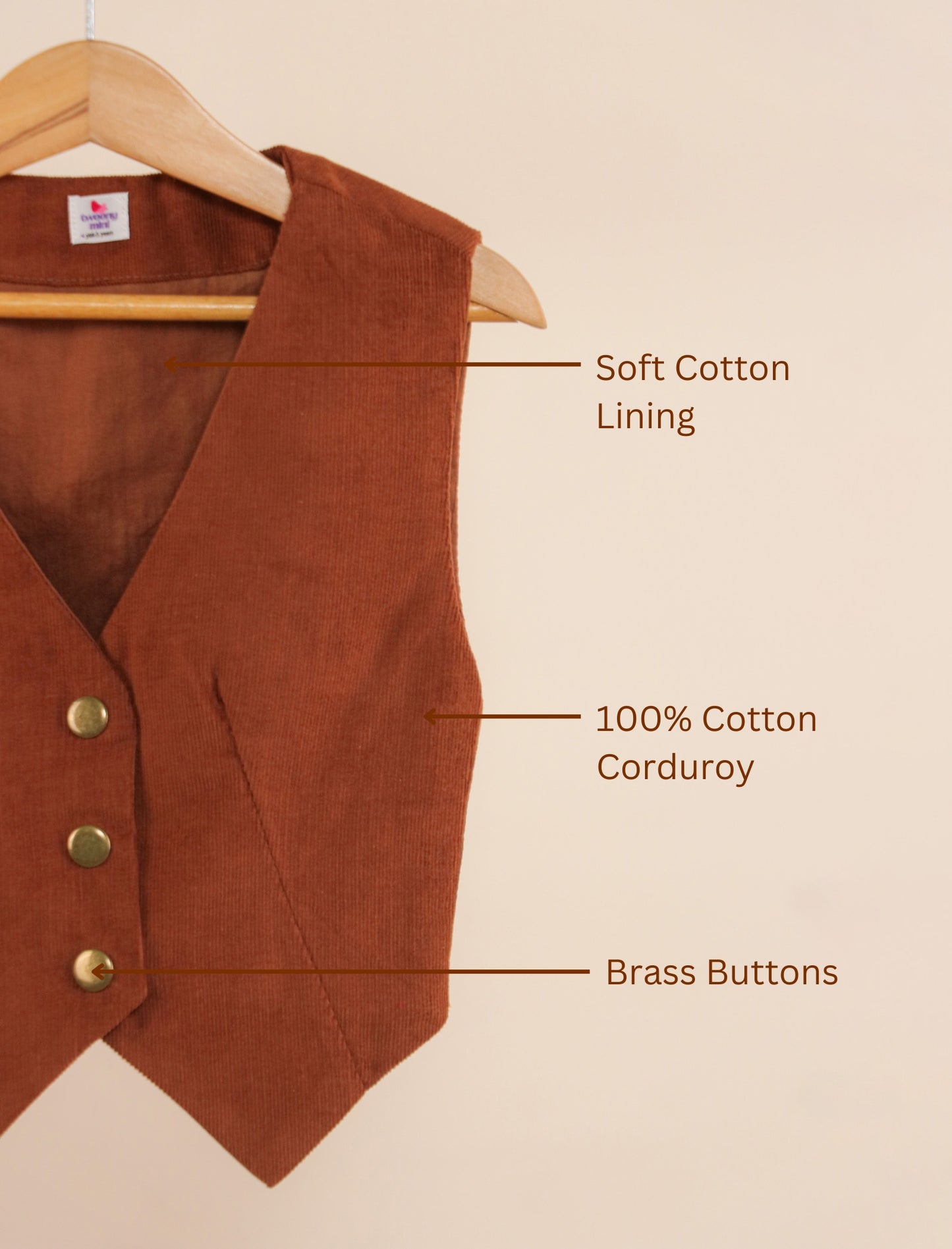 Brown vest on a hanger with text labels indicating features like soft cotton lining, 100% cotton corduroy, and brass buttons.