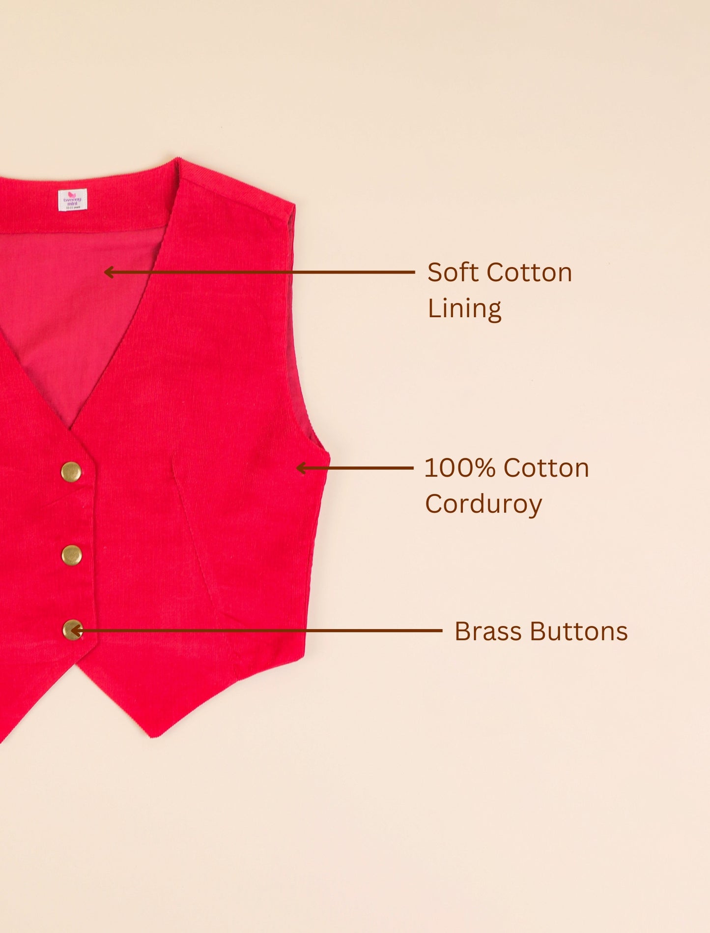 Red vest with labels indicating soft cotton lining, 100% cotton corduroy, and brass buttons on a beige background.