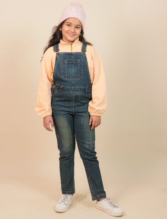 Girls wearing a peach jacket, denim overalls, and white sneakers on a beige background