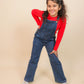 Girls wearing blue denim overalls and a red shirt on a beige background