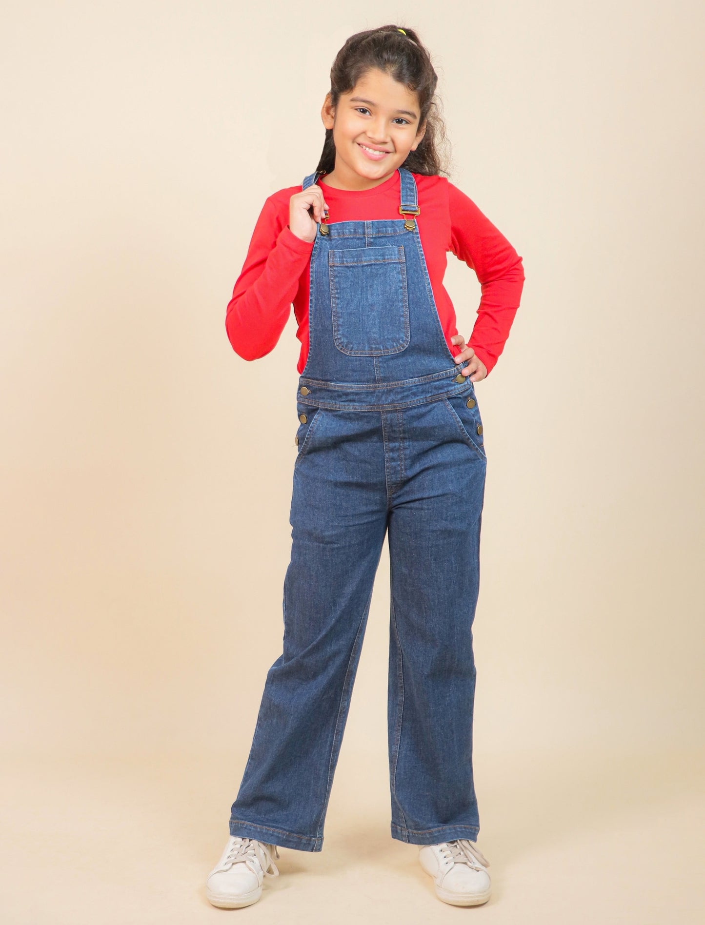 Girls wearing a red shirt and blue denim overalls on a beige background