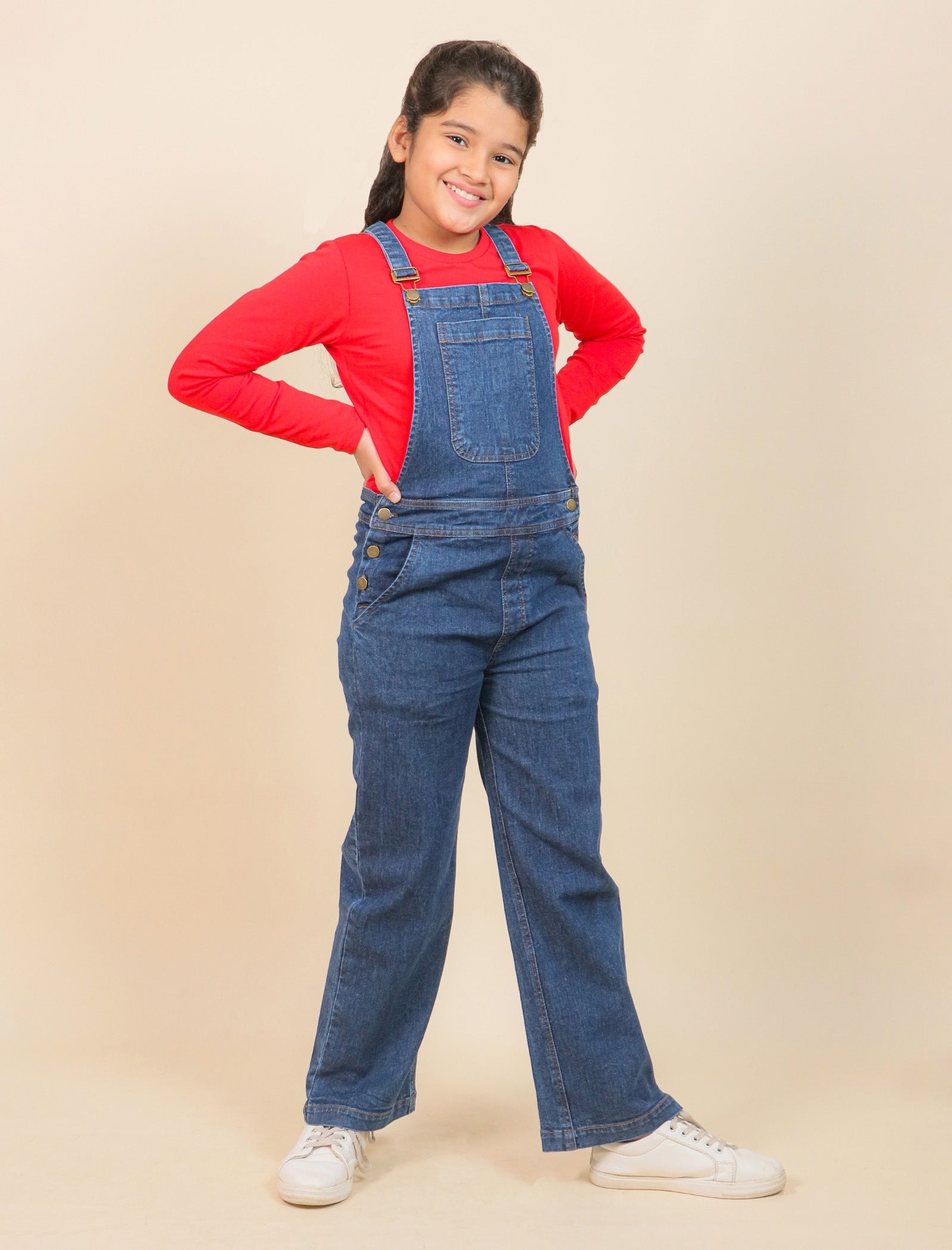 Girls wearing a red shirt and blue denim overalls on a beige background