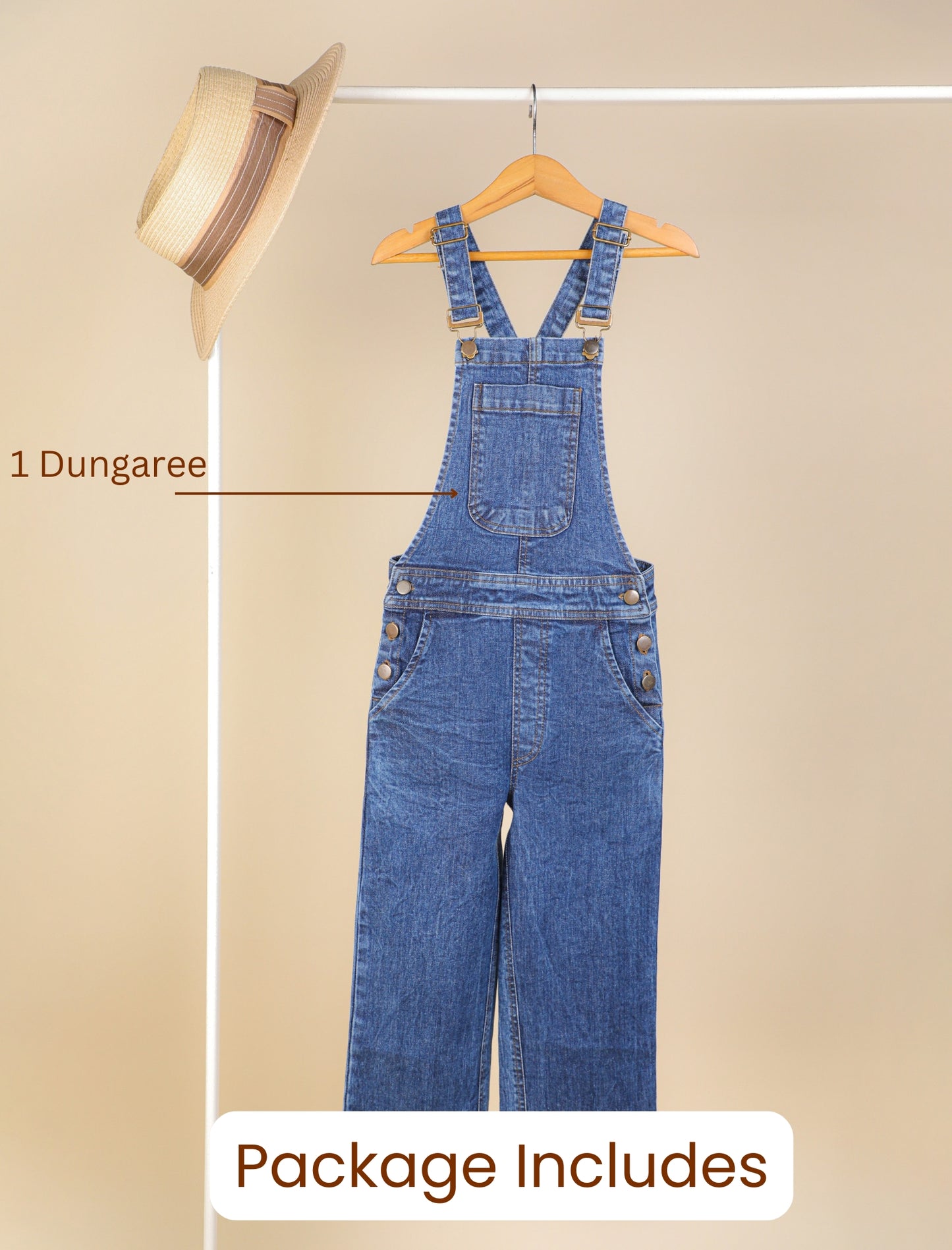 Blue denim dungaree on a hanger against a beige background