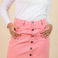 girls wearing a pink denim skirt with button details on a beige backgrounds