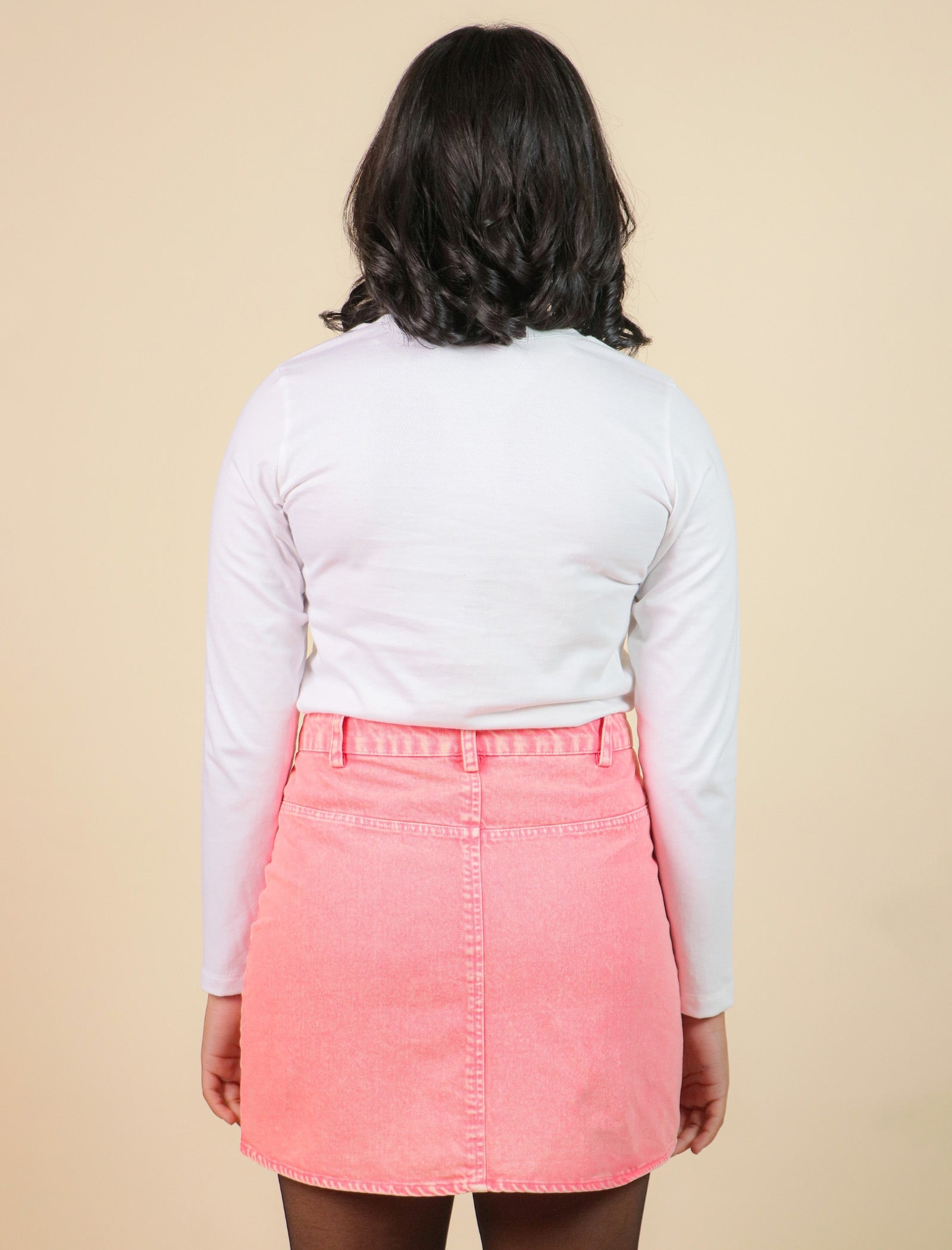 Girls wearing a white long-sleeve shirt and pink skirt on a beige background