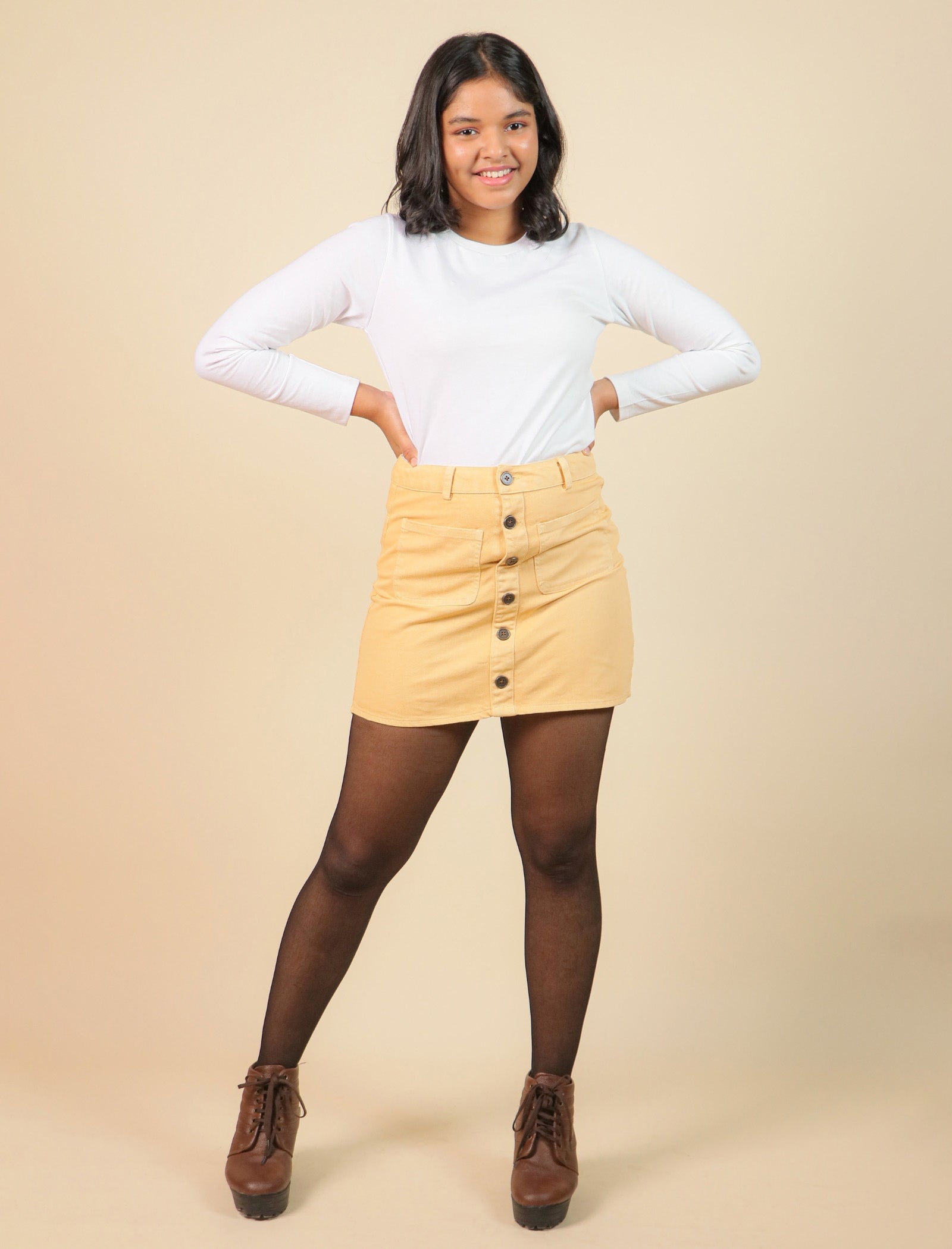 Girls wearing a white long-sleeve top and beige skirt on a beige background