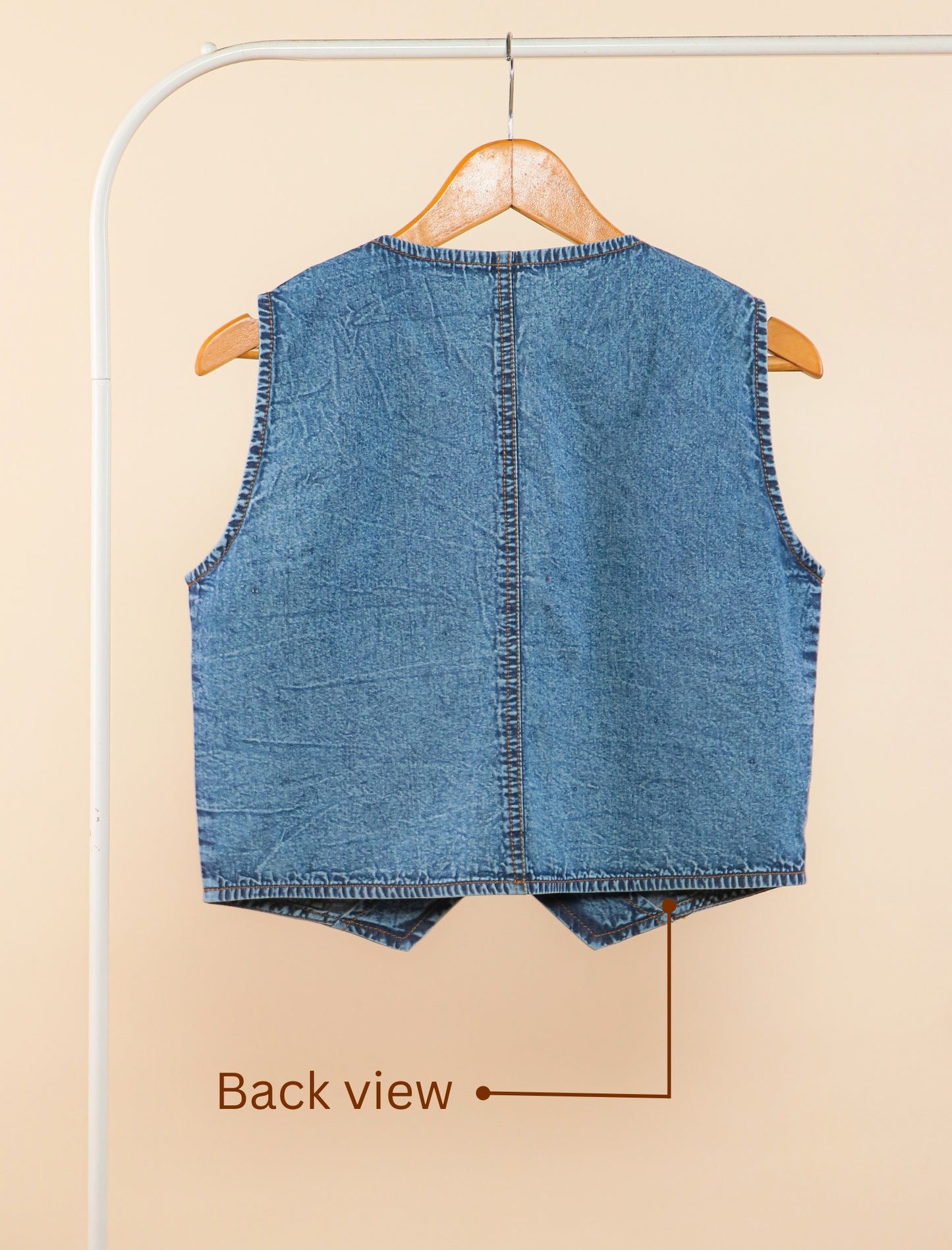 Blue denim vest on a hanger with 'Back view' text on a beige background