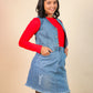 Girls wearing a denim dress over a red shirt on a beige background