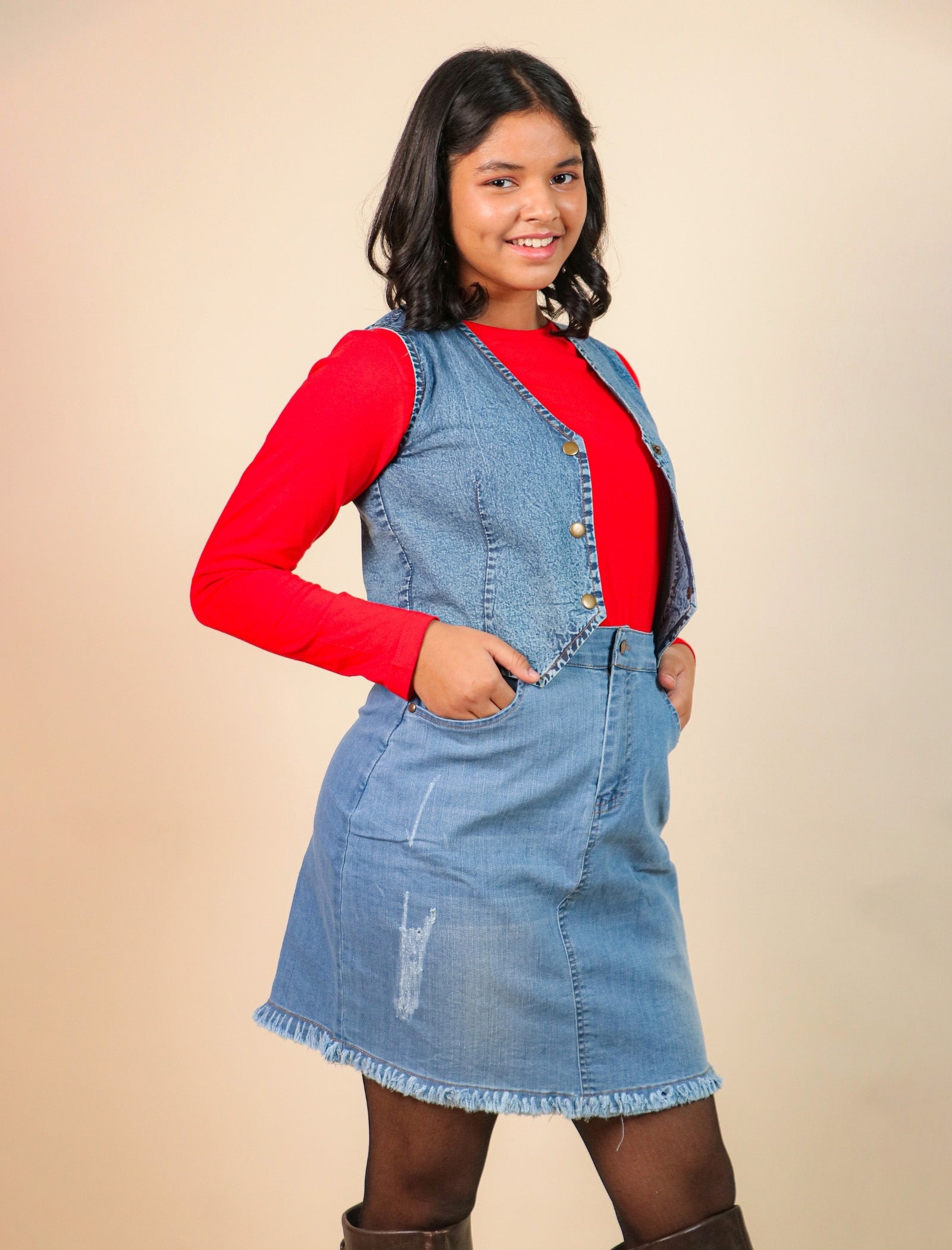 Girls wearing a denim dress over a red shirt on a beige background