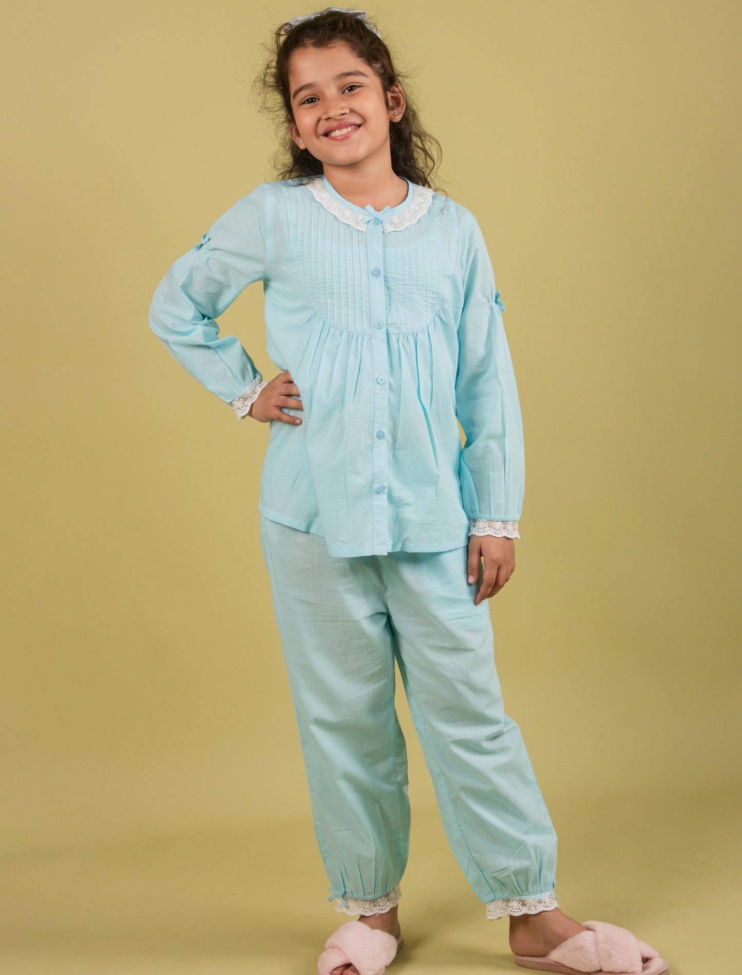 Girl wearing a light blue outfit with white lace trim on a beige background