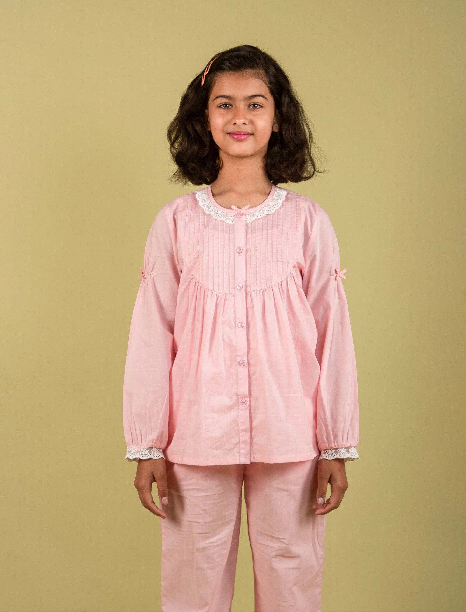 Girls wearing a pink pajama set against a beige background