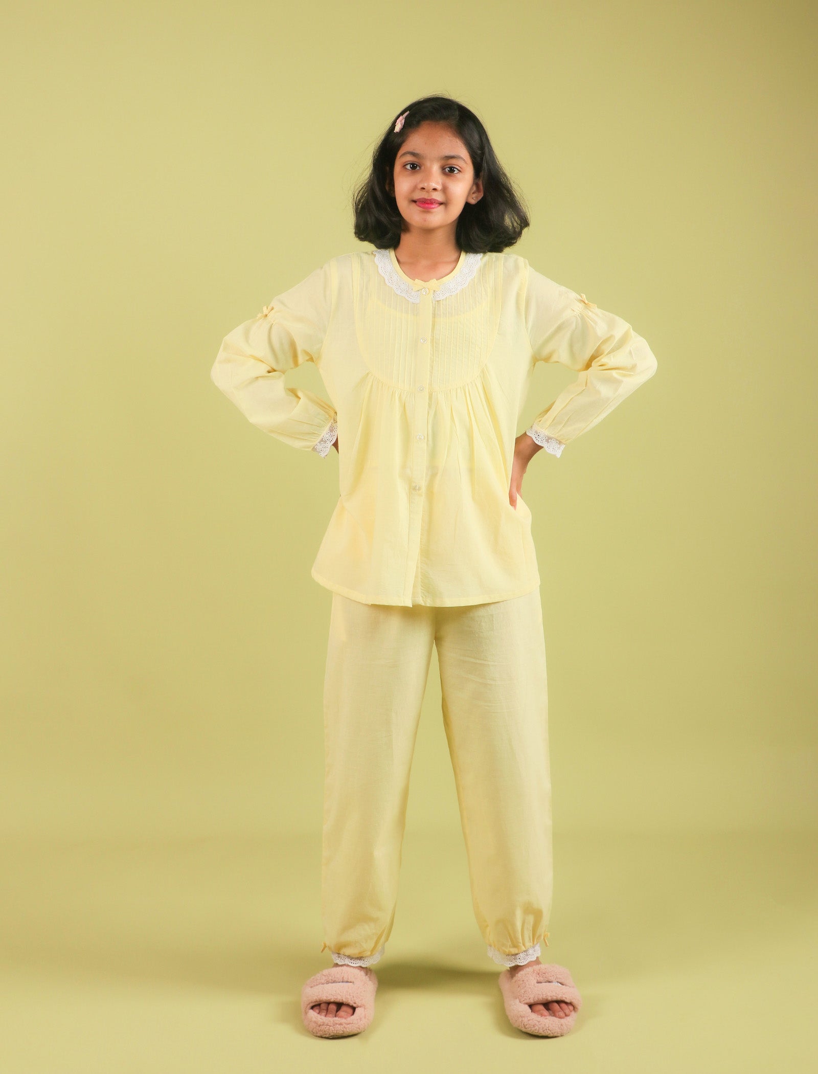 Girls wearing a yellow outfit with pink slippers on a light green background