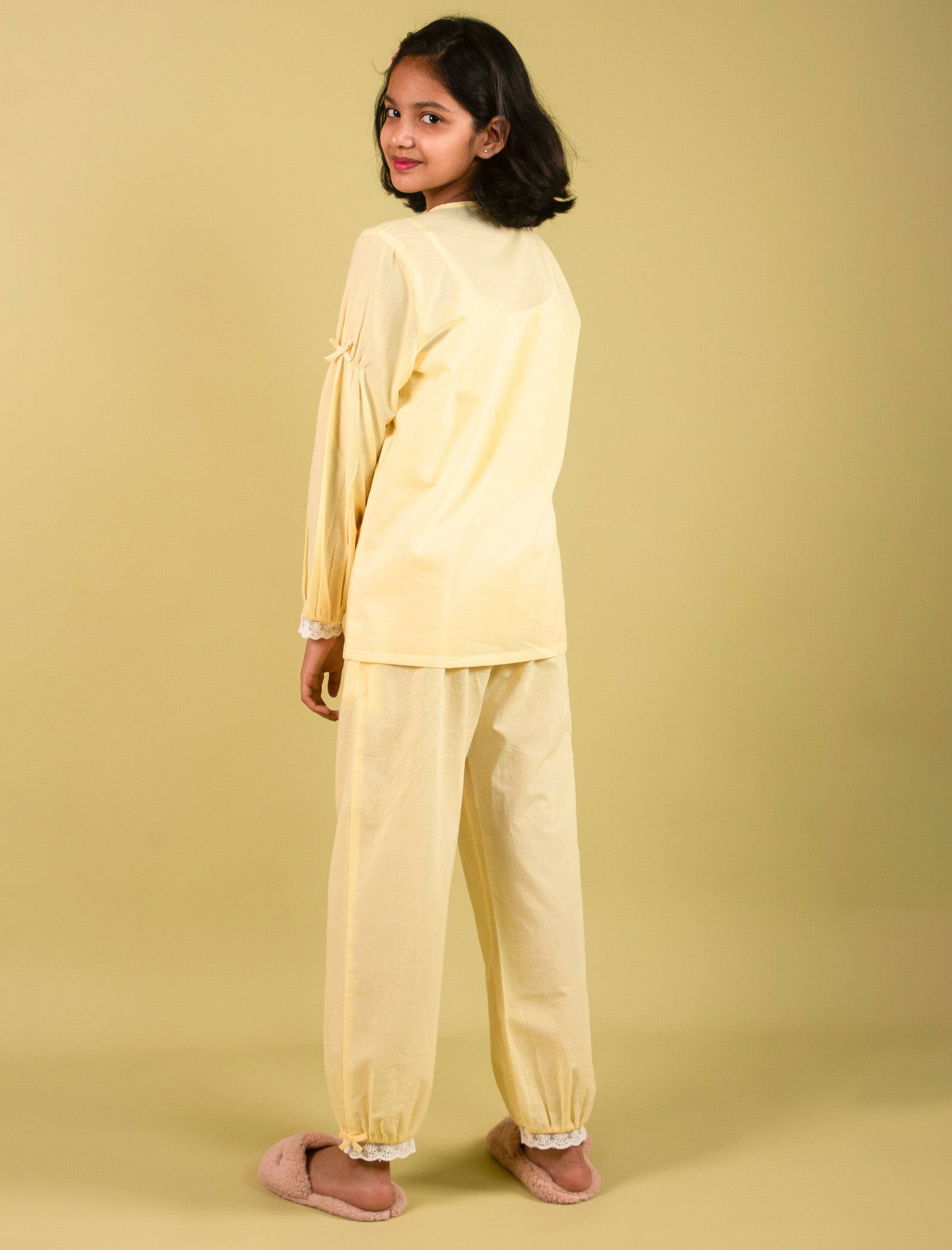 Girls wearing a light yellow outfit against a beige background