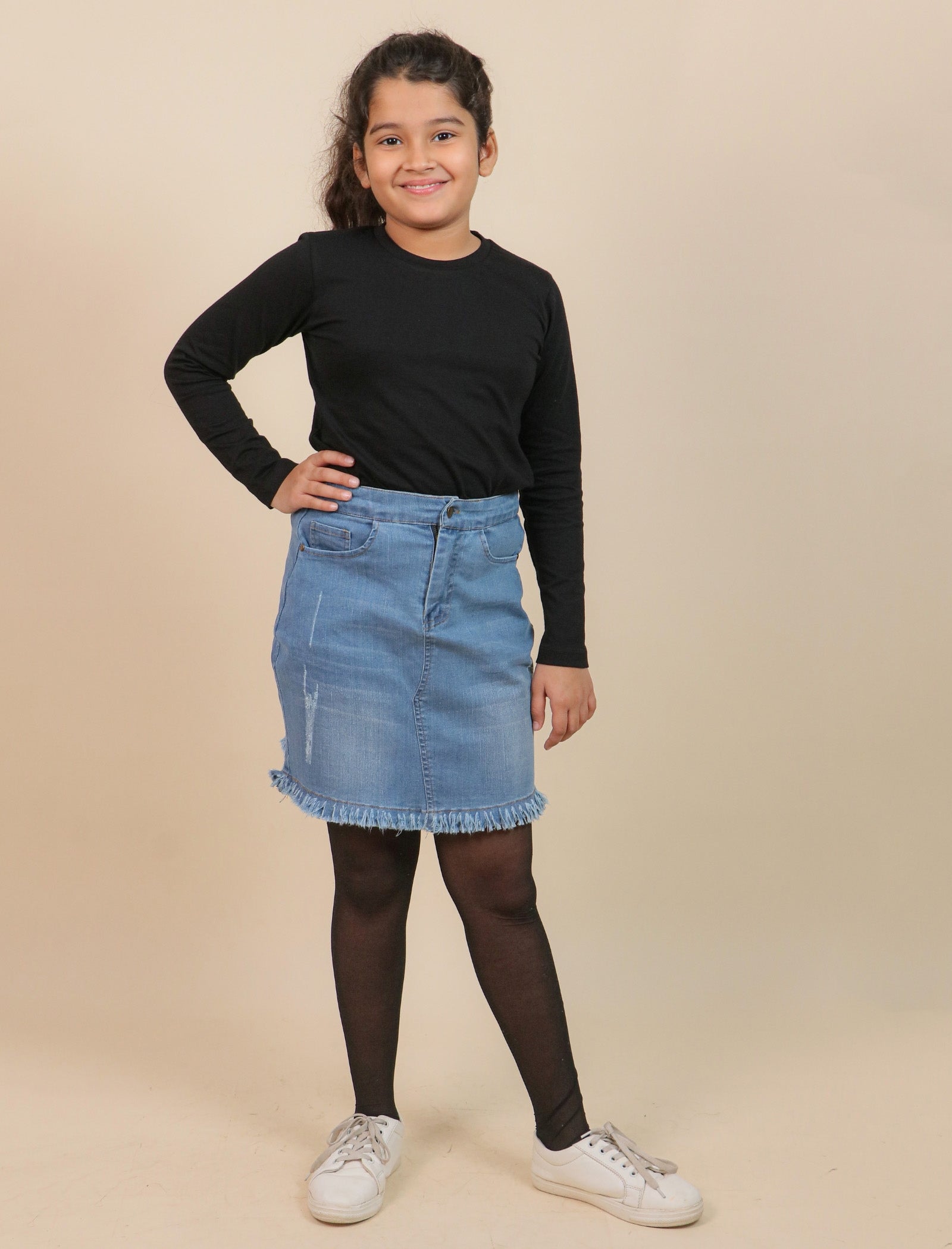 Girls wearing a black long-sleeve top and blue denim skirt on a beige background
