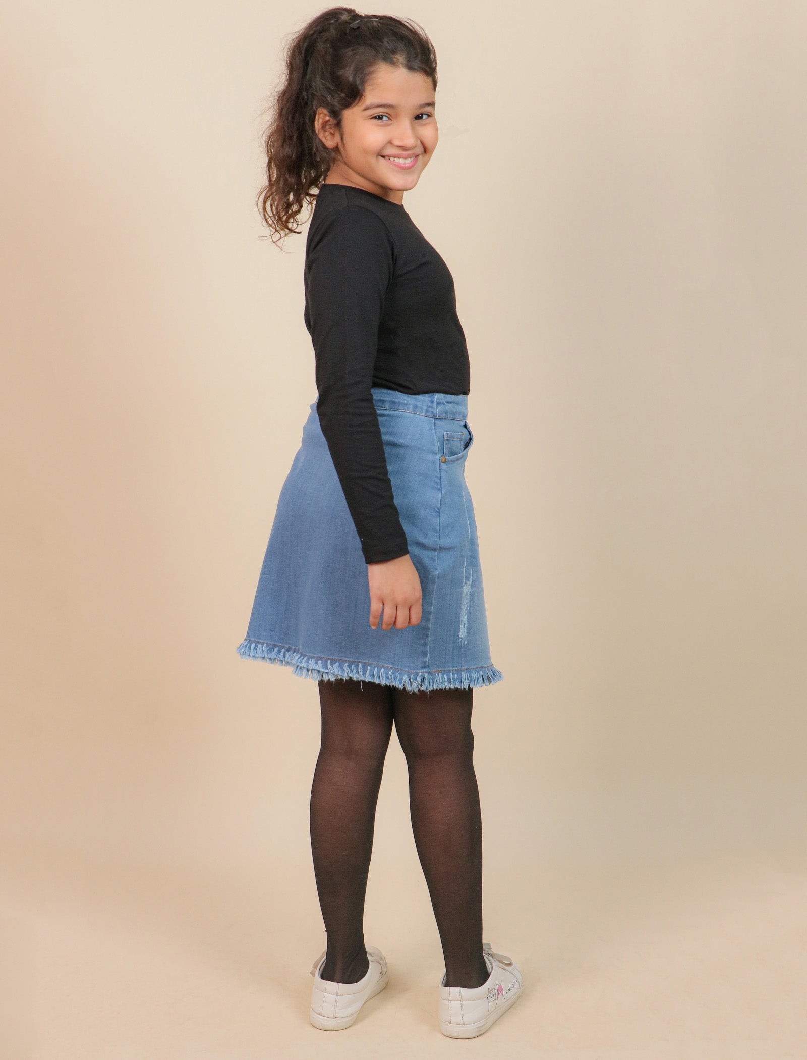 girl wearing a black top and blue denim skirt on a beige background