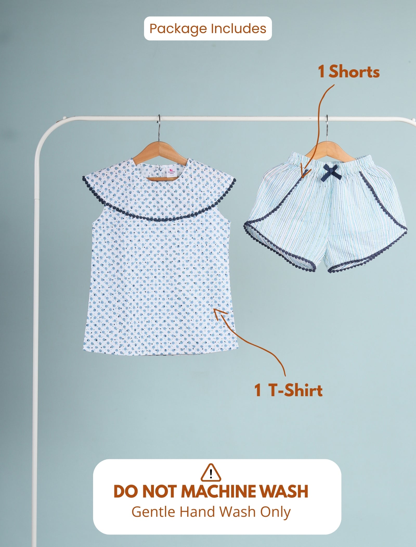 Girls clothing set with t-shirt and shorts on a hanger against a light blue background.