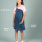 Girl wearing a denim pinafore dress with text labels on a gray background