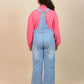 Girls wearing blue denim overalls and a pink shirt on a beige background