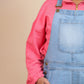 Girls wearing a pink shirt and blue denim overalls on a beige background