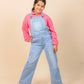 Girls wearing a pink hoodie and blue denim overalls on a beige background