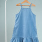 Blue denim dress on a hanger against a gray background