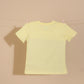 Yellow t-shirt on a clothesline against a beige wall