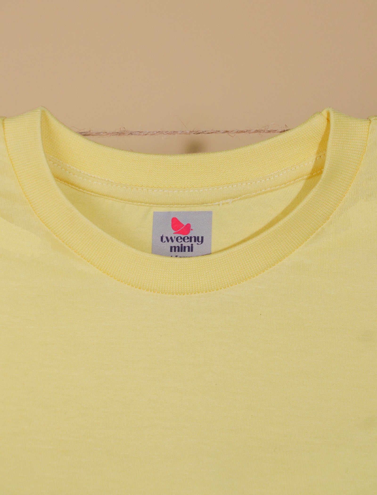 Yellow t-shirt with a brand label on a beige background