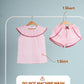 Children's clothing set with a shirt and shorts on hangers against a gray background.