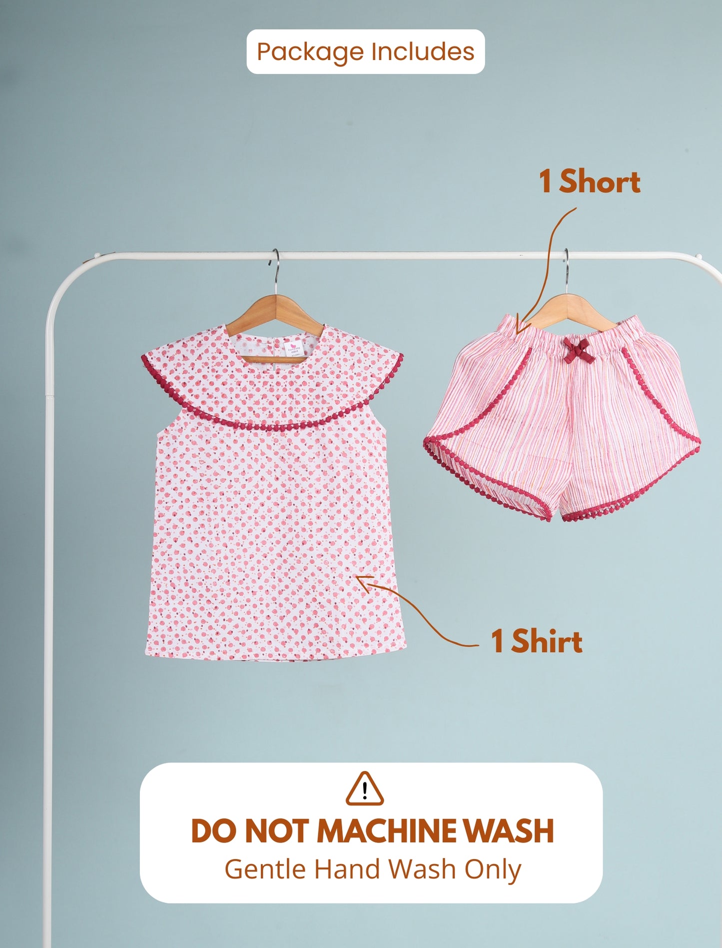 Children's clothing set with a shirt and shorts on hangers against a gray background.
