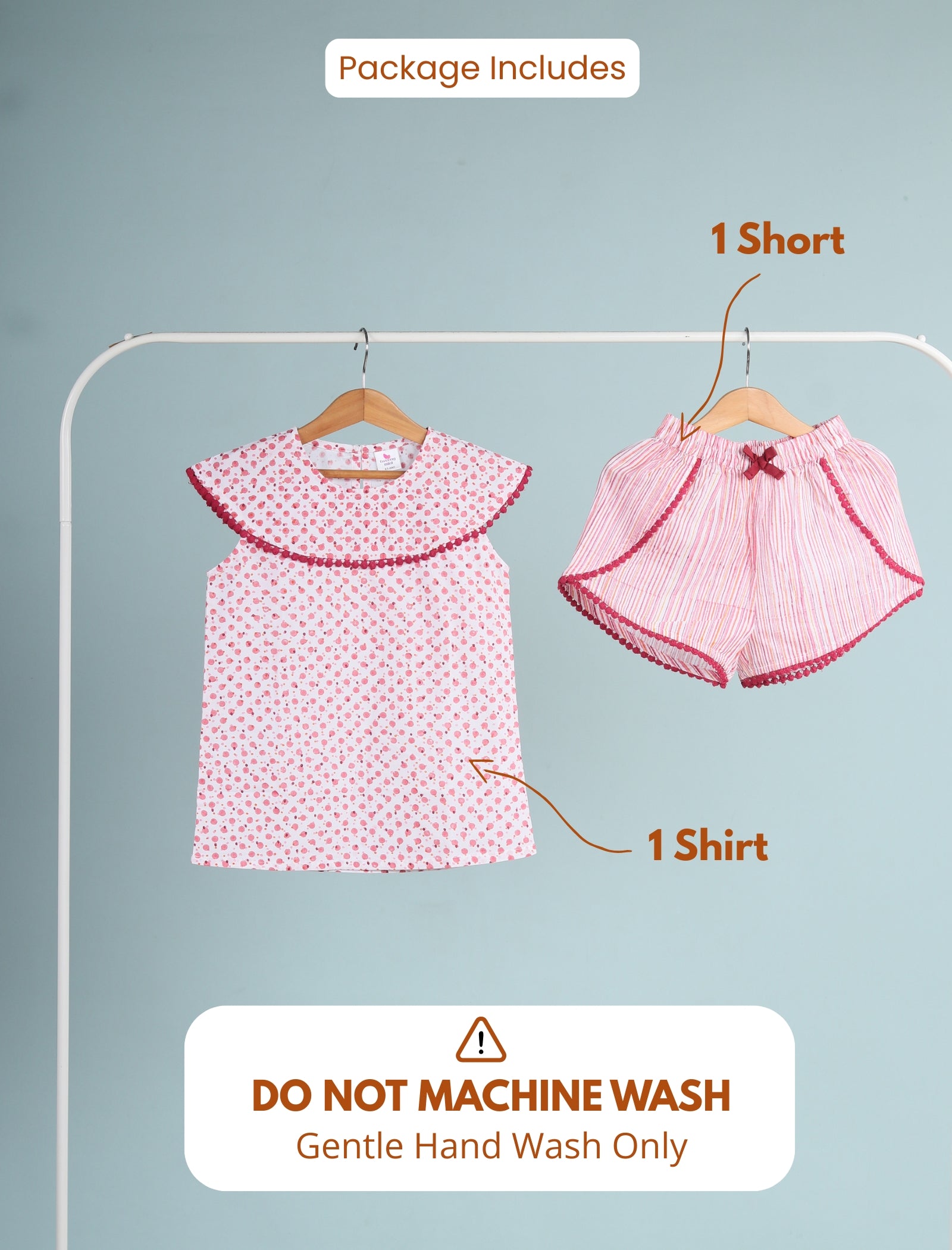 Children's clothing set with a shirt and shorts on hangers against a gray background.