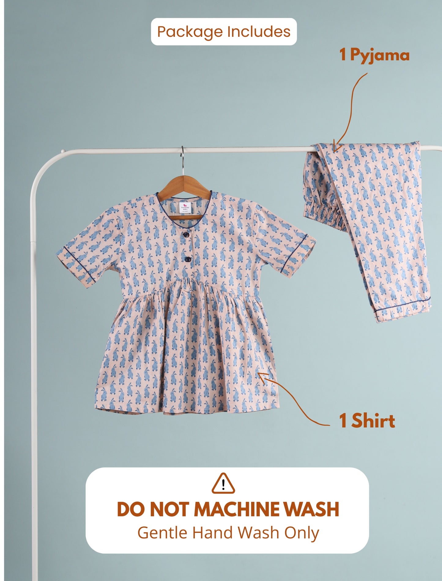 Girls outfit with shirt and pyjama on a hanger against a light blue background.