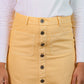 Yellow skirt with buttons worn by a person, against a neutral background