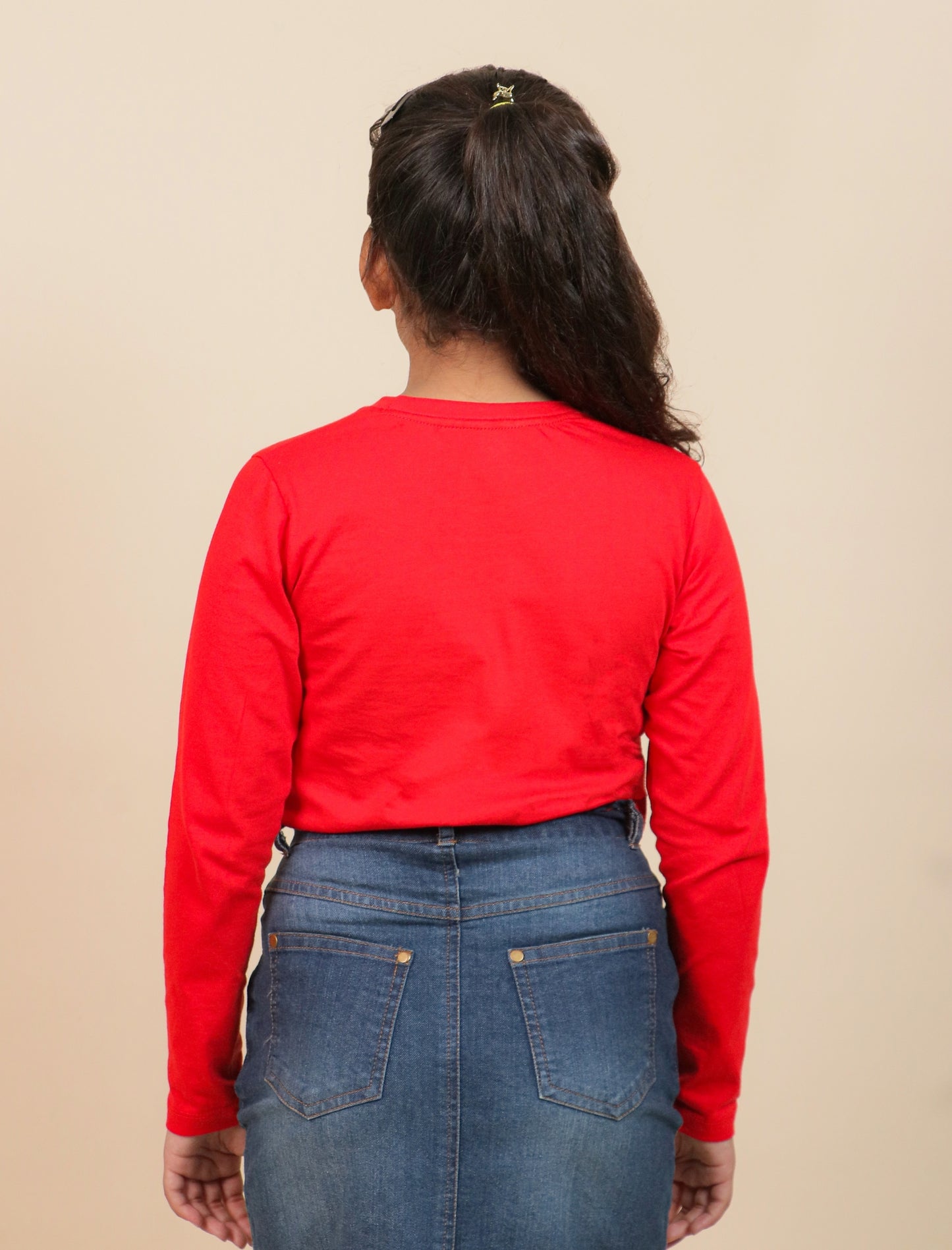 Girls wearing a red long-sleeve shirt and blue jeans on a beige background