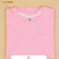 Folded pink t-shirt with a label on a beige background