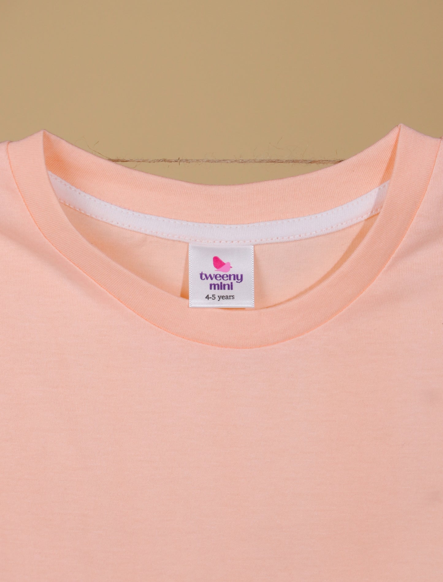 Close-up of a peach-colored shirt with a label on a beige background