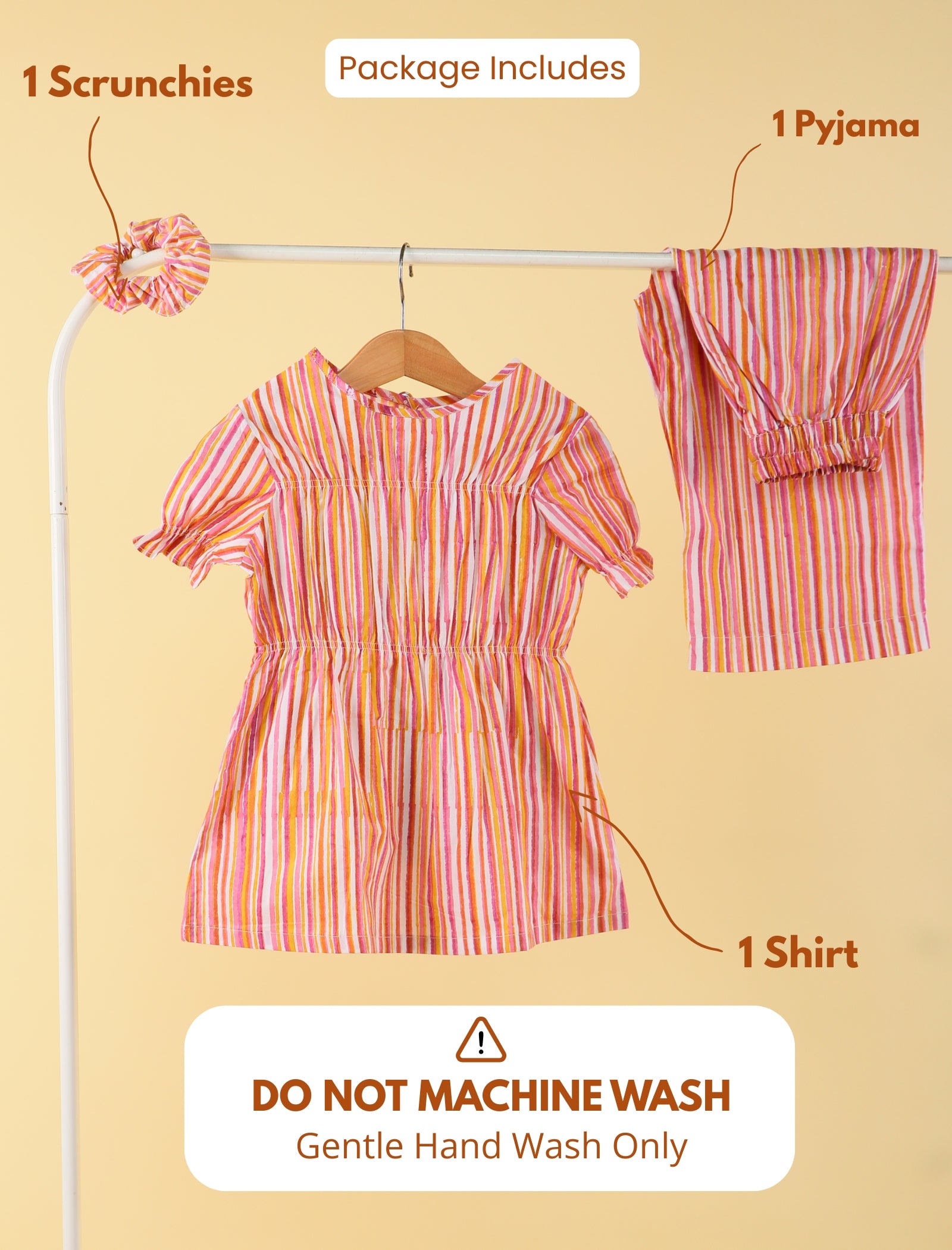 Girls clothing set with dress, shirt, and scrunchies on a rack against a beige background.