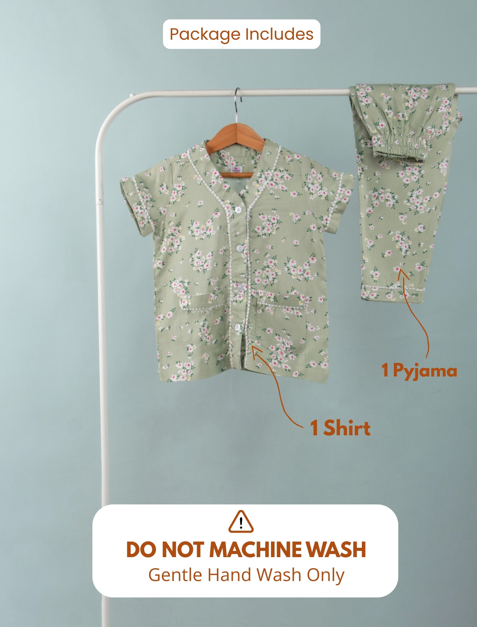 Girl green floral outfit with shirt and pyjama on a hanger against a light blue background.