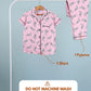 Pink pajama set with shirt and pants on a hanger against a light blue background.
